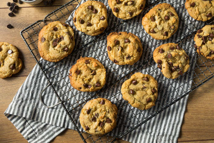 Cooling rack full of chocolate chip cookies on a wooden counter